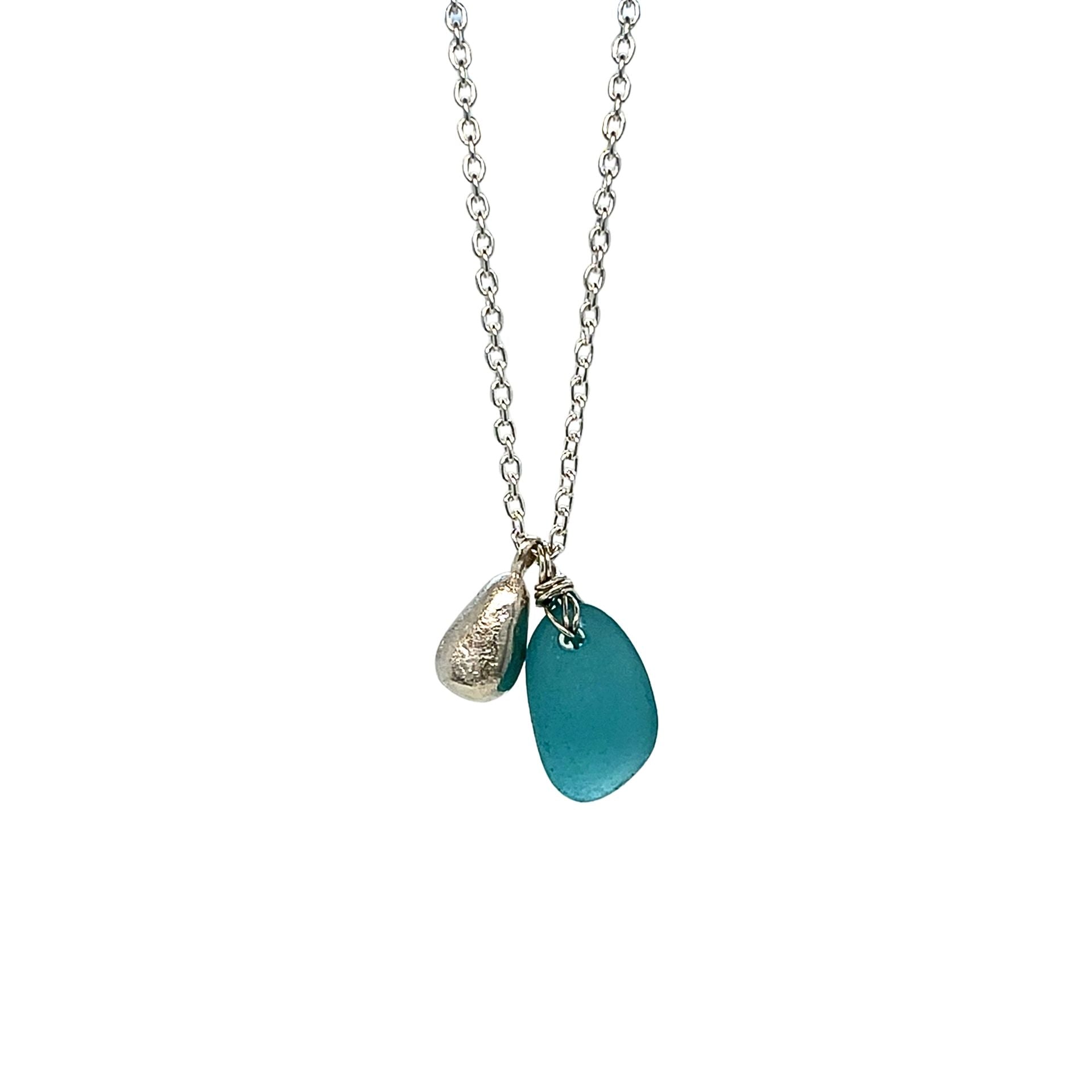 Close-up of silver nugget cast from sea glass beside turquoise pendant