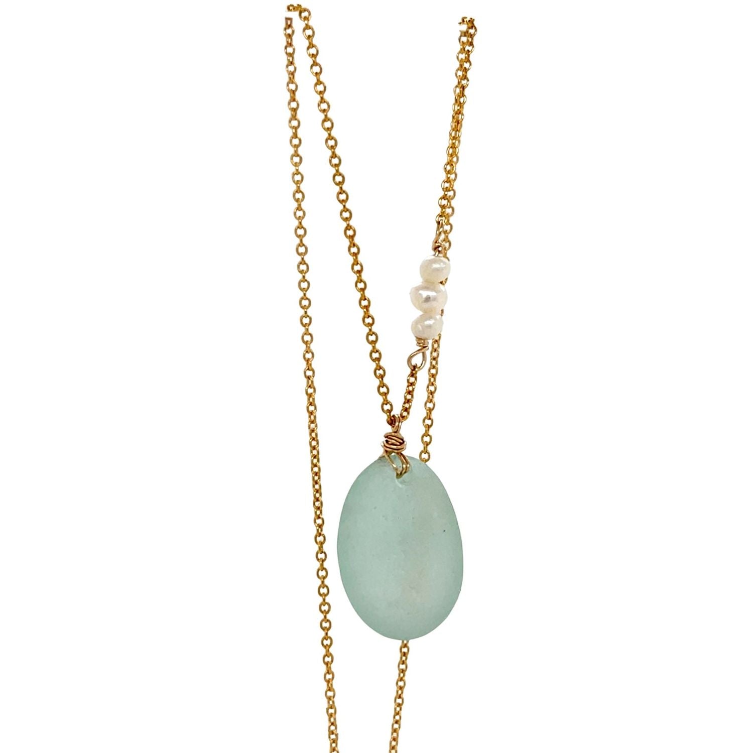 Close-up of a seafoam sea glass pendant with gold-filled chain and delicate pearl accent, one of a kind necklace.
